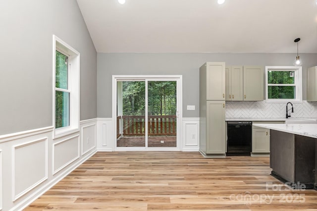 kitchen with a healthy amount of sunlight, vaulted ceiling, light countertops, and dishwasher