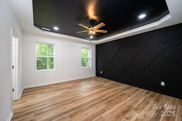 spare room with light wood-style flooring, a tray ceiling, ceiling fan, and recessed lighting