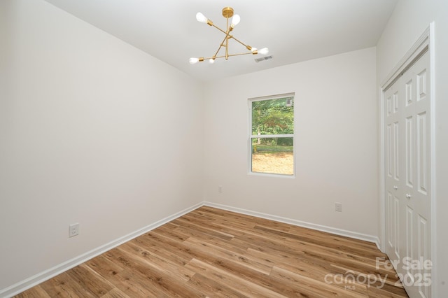 unfurnished bedroom with light wood-style flooring, a closet, visible vents, and a notable chandelier