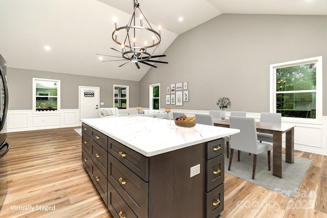 kitchen with open floor plan, plenty of natural light, a kitchen island, and light wood-style floors