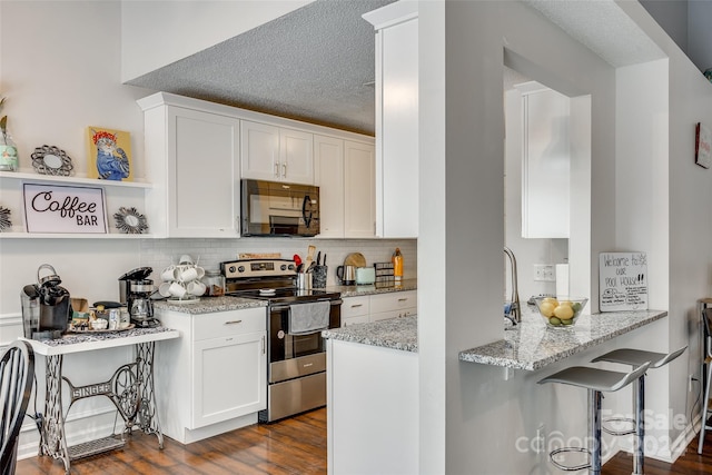 kitchen featuring a textured ceiling, dark hardwood / wood-style floors, light stone countertops, electric range, and white cabinetry