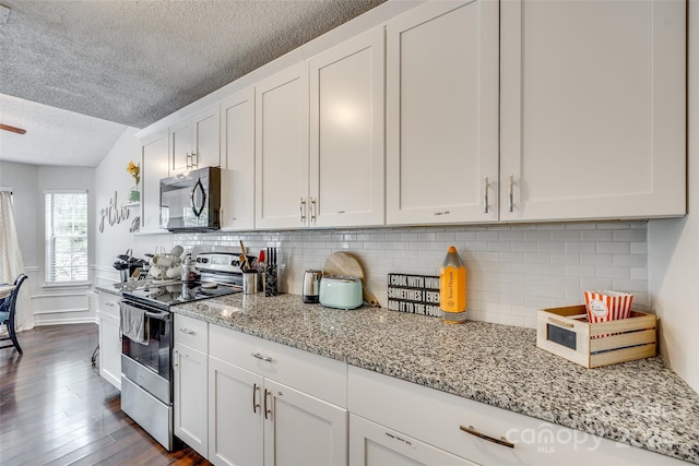 kitchen with a textured ceiling, dark wood-type flooring, stainless steel appliances, light stone counters, and white cabinets