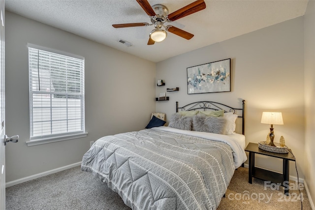 bedroom with a textured ceiling, carpet, and ceiling fan