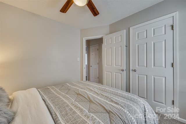 bedroom with a textured ceiling, carpet flooring, and ceiling fan