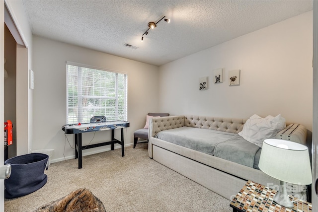 carpeted bedroom with track lighting and a textured ceiling