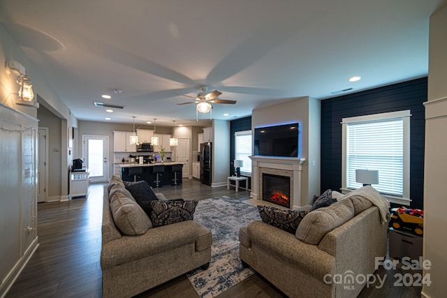 living room with ceiling fan and dark wood-type flooring