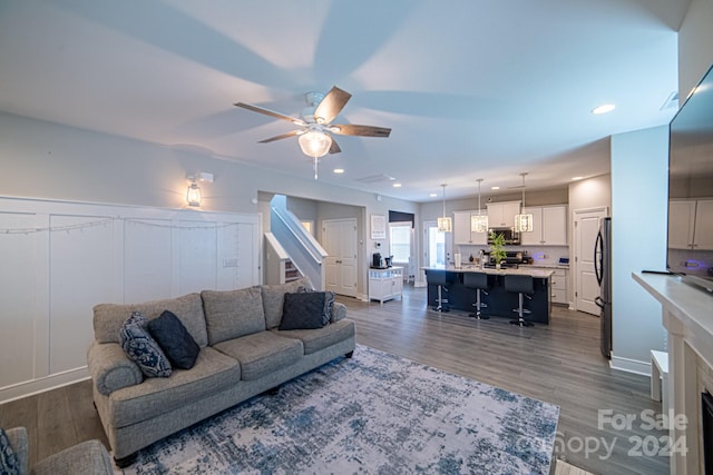 living room featuring ceiling fan and dark wood-type flooring