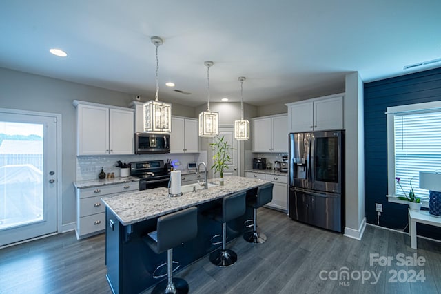 kitchen with white cabinets, appliances with stainless steel finishes, a center island with sink, and a wealth of natural light