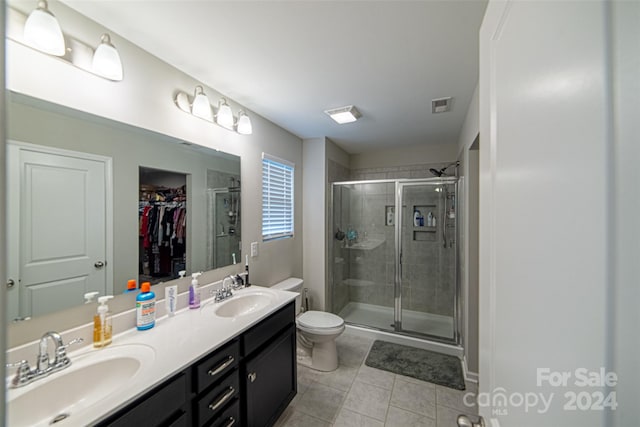 bathroom featuring toilet, vanity, tile patterned floors, and a shower with shower door