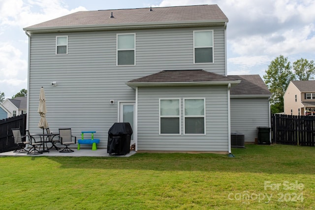 back of property with a lawn, central air condition unit, and a patio