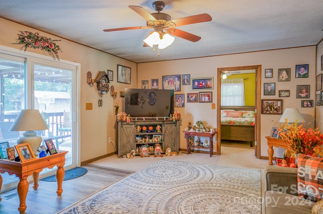 living room featuring light hardwood / wood-style flooring, ceiling fan, and a textured ceiling