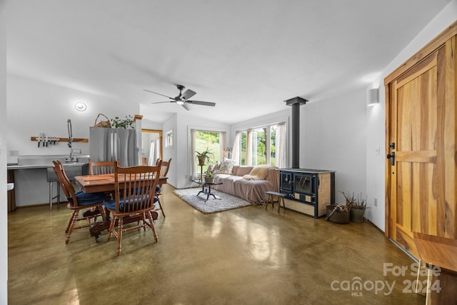 dining area featuring a wood stove and ceiling fan