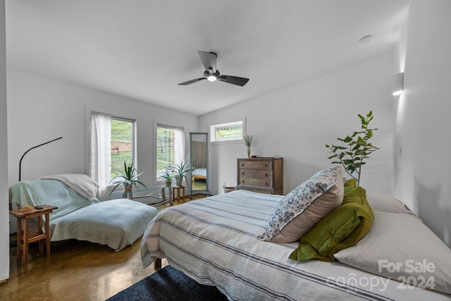 bedroom with ceiling fan, lofted ceiling, and concrete flooring