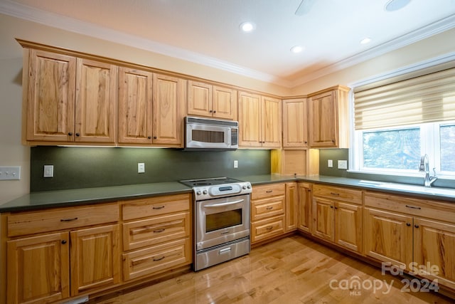 kitchen featuring stainless steel appliances, ornamental molding, sink, and light hardwood / wood-style floors