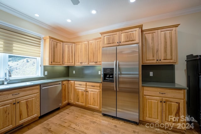 kitchen featuring crown molding, appliances with stainless steel finishes, sink, and light hardwood / wood-style floors