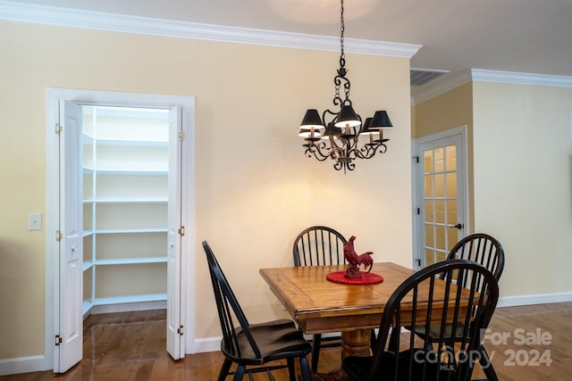 dining area with a notable chandelier, wood-type flooring, and crown molding