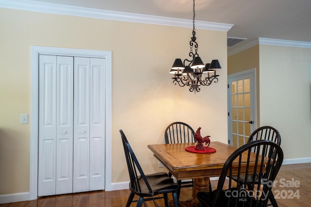 dining area with hardwood / wood-style floors, an inviting chandelier, and ornamental molding