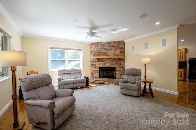 living room featuring ornamental molding, hardwood / wood-style floors, ceiling fan, and a stone fireplace