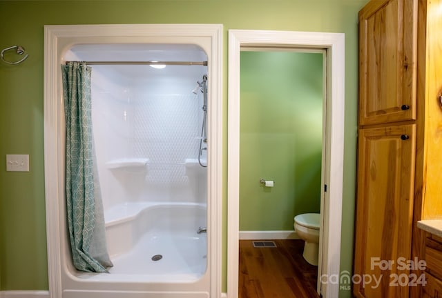 bathroom with a shower with shower curtain, wood-type flooring, toilet, and vanity