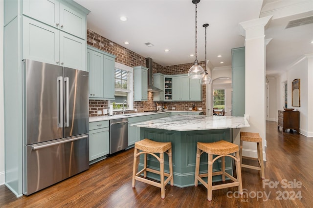 kitchen featuring plenty of natural light, appliances with stainless steel finishes, dark hardwood / wood-style flooring, and wall chimney exhaust hood