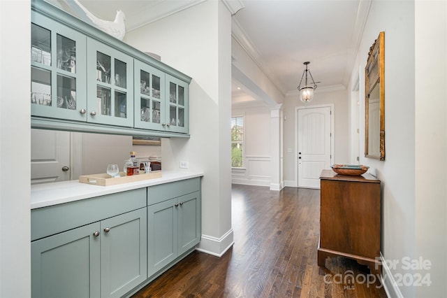 bar featuring dark wood-type flooring, ornamental molding, decorative light fixtures, and green cabinetry