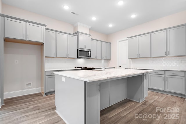 kitchen featuring gray cabinetry, a center island with sink, and light hardwood / wood-style floors