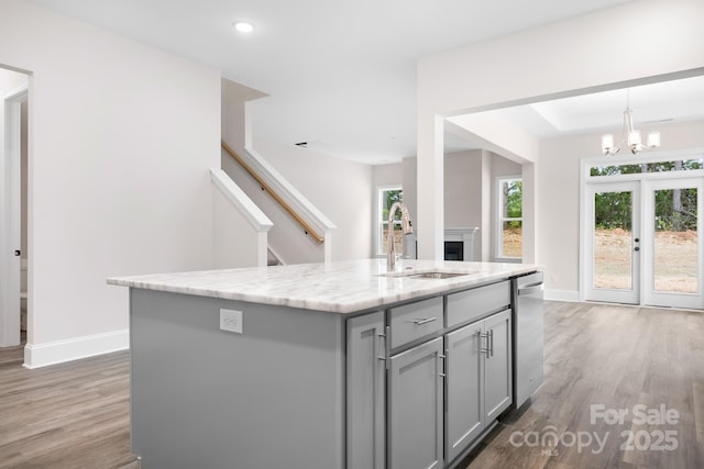 kitchen with a kitchen island with sink, sink, dark wood-type flooring, and stainless steel dishwasher