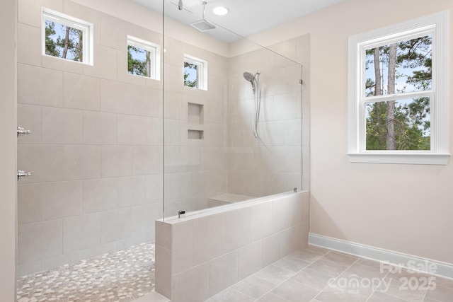 bathroom featuring tile patterned flooring, a wealth of natural light, and tiled shower