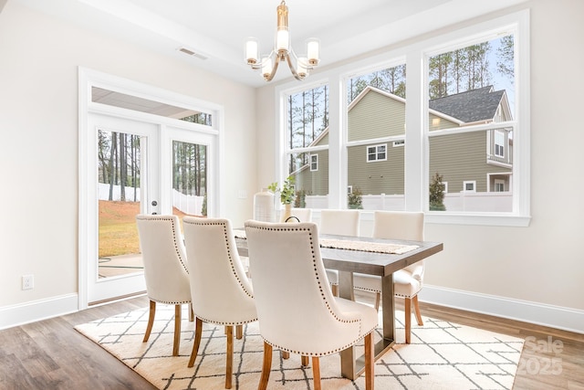 dining space featuring light wood-type flooring and a notable chandelier