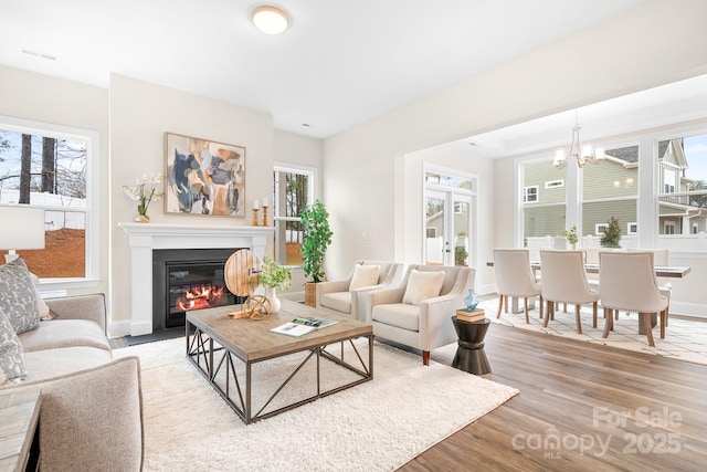 living room with a notable chandelier, light hardwood / wood-style floors, and french doors