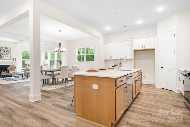 kitchen featuring white cabinetry, a kitchen island with sink, sink, and light hardwood / wood-style flooring