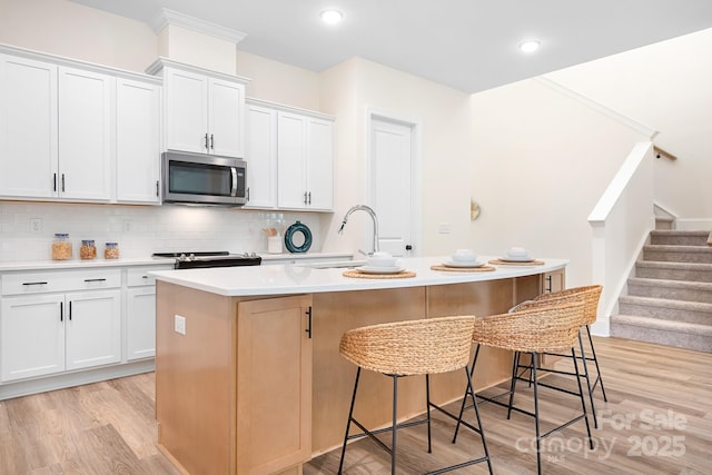 kitchen featuring white cabinetry, a kitchen island with sink, and light hardwood / wood-style floors