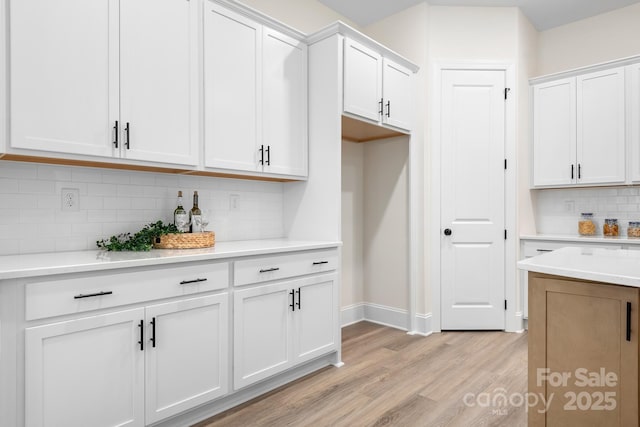 kitchen with tasteful backsplash, white cabinetry, and light hardwood / wood-style floors