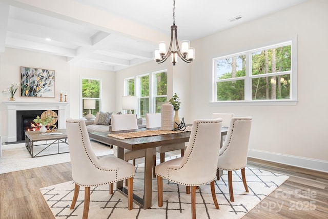 dining space with beamed ceiling, light hardwood / wood-style floors, an inviting chandelier, and coffered ceiling