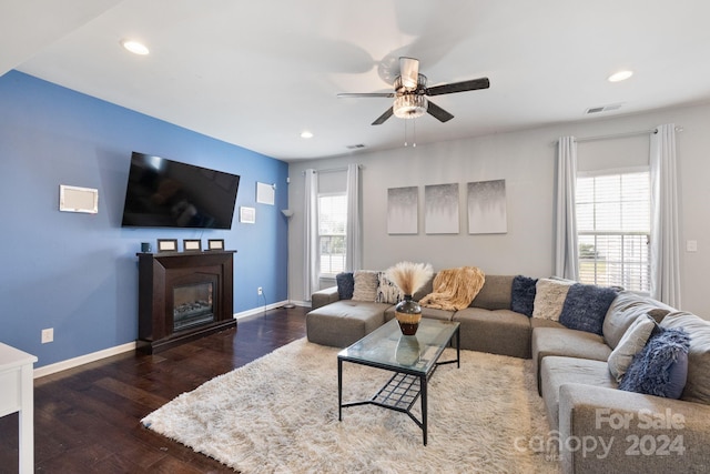 living room featuring dark wood-type flooring, ceiling fan, and a wealth of natural light