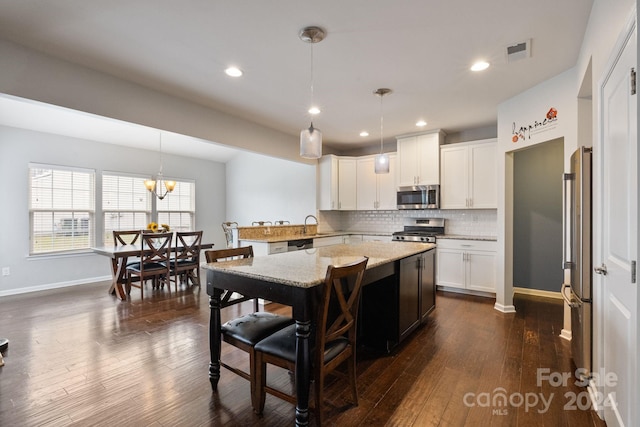 kitchen with stainless steel appliances, decorative light fixtures, and dark hardwood / wood-style floors