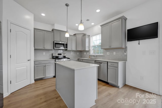 kitchen featuring decorative light fixtures, stainless steel appliances, a kitchen island, and gray cabinetry