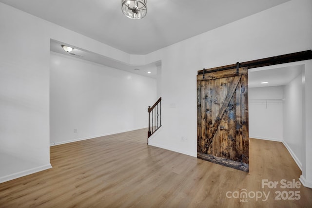 unfurnished room featuring a barn door and light hardwood / wood-style floors