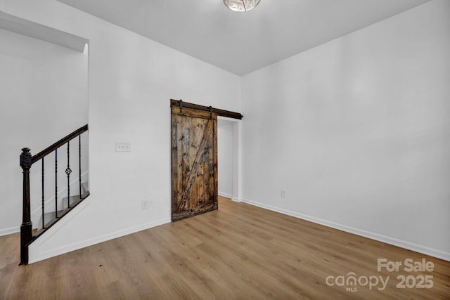 empty room featuring a barn door and light hardwood / wood-style floors