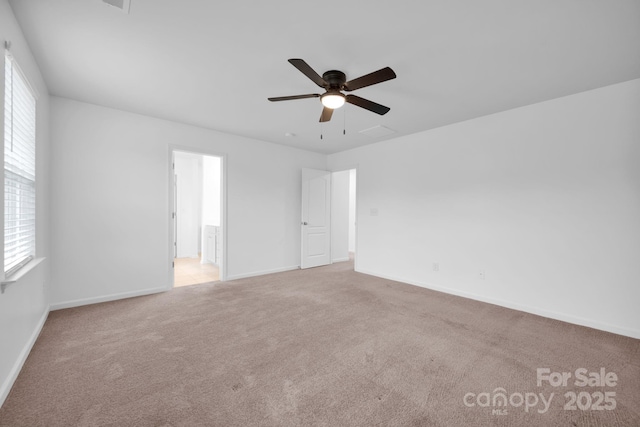 empty room with ceiling fan, light colored carpet, and a wealth of natural light