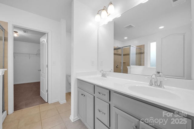 bathroom featuring tile patterned flooring, vanity, toilet, and a shower with shower door