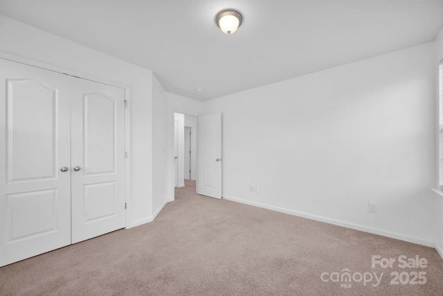 unfurnished bedroom featuring light carpet and a closet