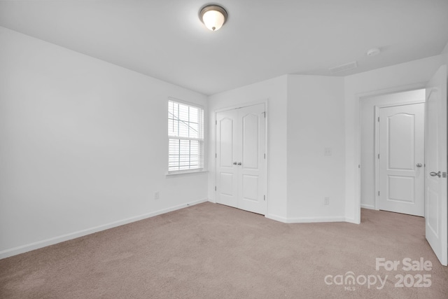 unfurnished bedroom featuring light colored carpet and a closet