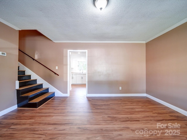 empty room with crown molding, hardwood / wood-style floors, a textured ceiling, and sink