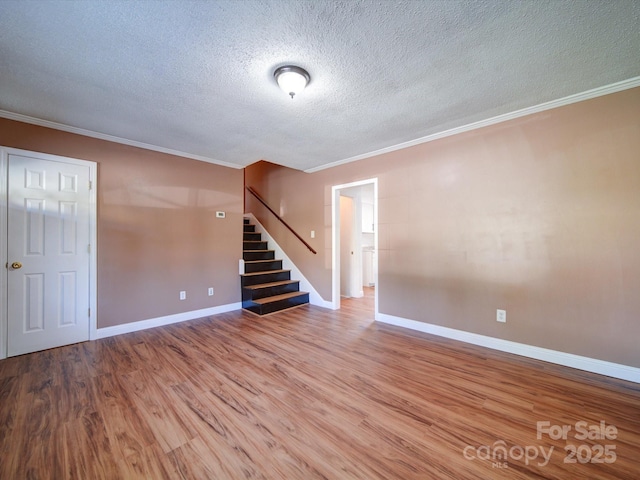 empty room with hardwood / wood-style floors, crown molding, and a textured ceiling