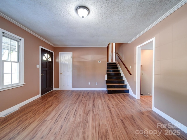 entrance foyer with a textured ceiling, light wood-type flooring, and ornamental molding