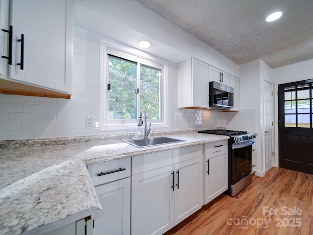 kitchen featuring white cabinets, light stone counters, sink, and stainless steel appliances