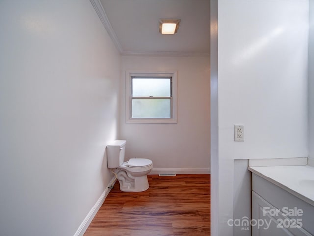 bathroom with wood-type flooring, vanity, toilet, and ornamental molding