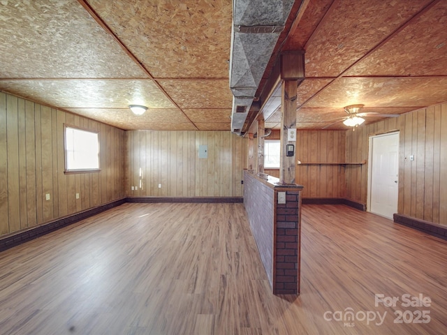 bonus room featuring wooden walls, plenty of natural light, and ceiling fan