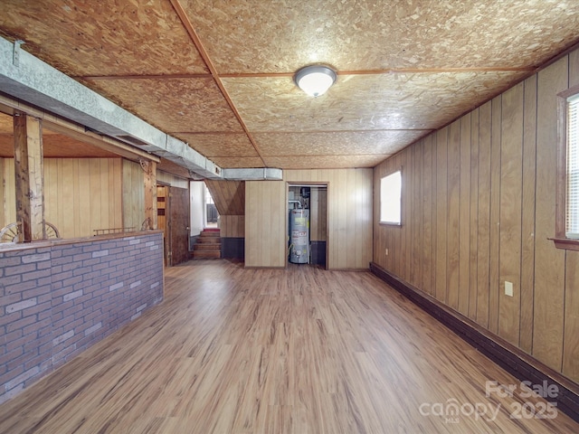 interior space featuring water heater, hardwood / wood-style floors, wooden ceiling, and wood walls